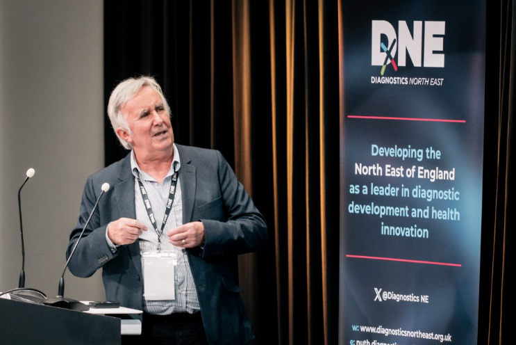 AD giving a talk with the DxNE banner behind him